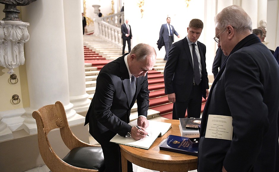 Vladimir Putin signs the distinguished visitors’ book at the State Hermitage. On the right: Director of the State Hermitage Mikhail Piotrovsky.