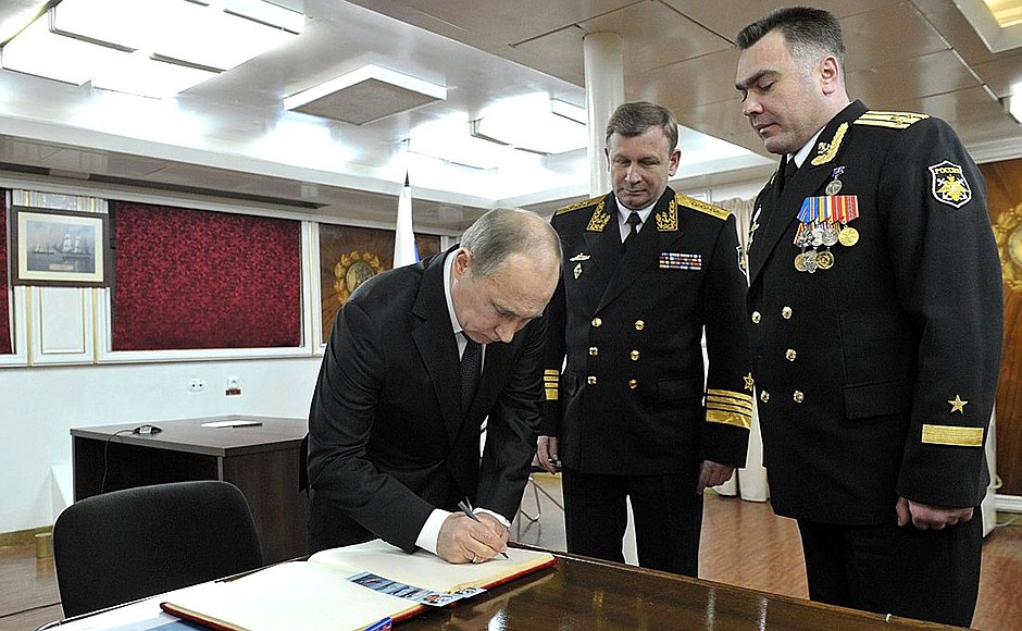 Vladimir Putin signs the distinguished visitors' book aboard cruiser Pyotr Veliky.