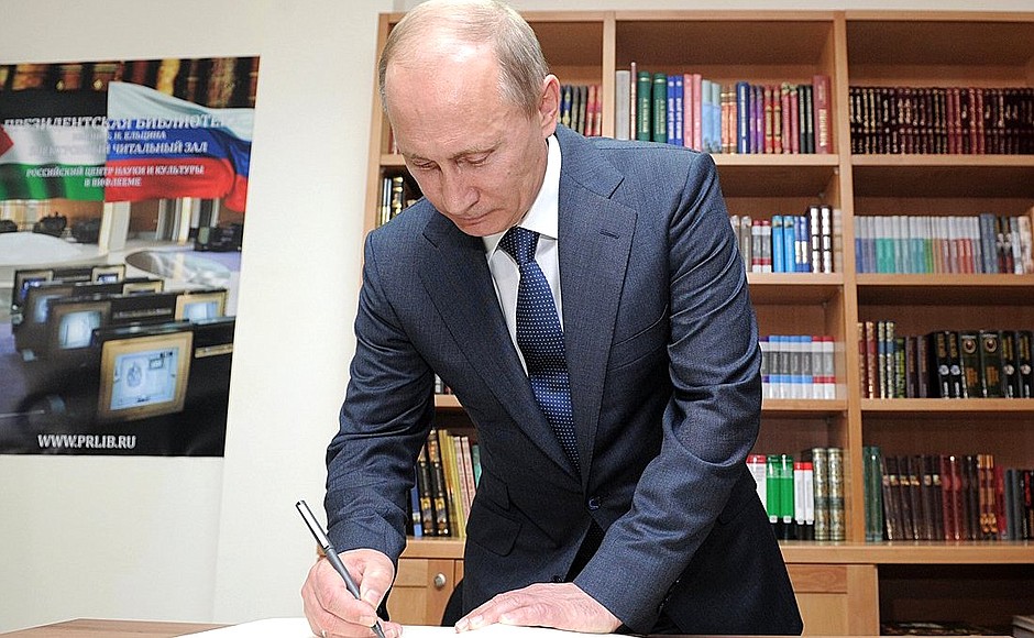 Vladimir Putin signs the distinguished visitors' book in the Russian Science and Culture Centre.