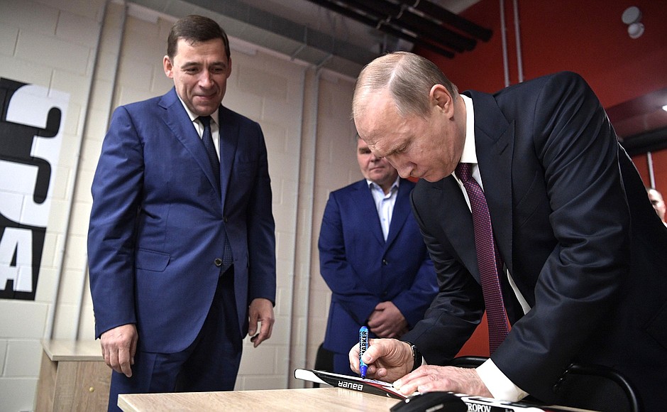 Vladimir Putin signs a hockey stick during his visit to the Datsyuk Arena sports complex.
