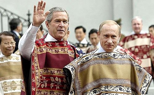 President Vladimir Putin and US President George W Bush wear Chilean ponchos as they arrive for an official APEC Leaders photo session at La Moneda palace.