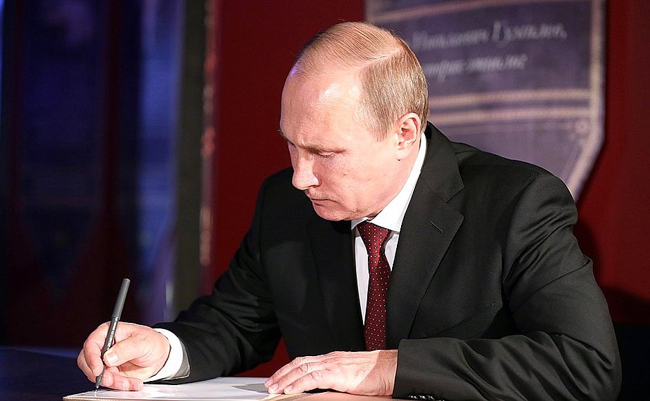 Vladimir Putin signs the distinguished visitors’ book during his visit to the exposition My History. The Rurik Dynasty.