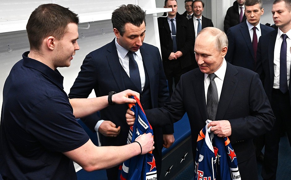 Vladimir Putin was given an ice hockey uniform during his visit to SKA Arena multi-purpose concert and sports complex. With First Vice-President of the Russian Hockey Federation, head coach of HC SKA Roman Rotenberg (second left).
