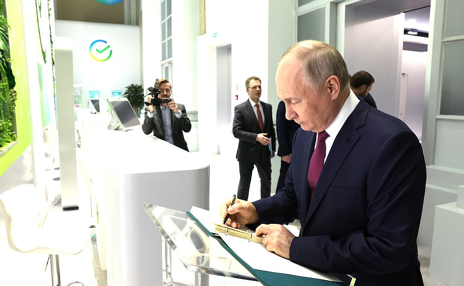 Vladimir Putin leaves a note in the book of honoured guests at the Sber pavilion at the RUSSIA EXPO International Exhibition and Forum at VDNKh.