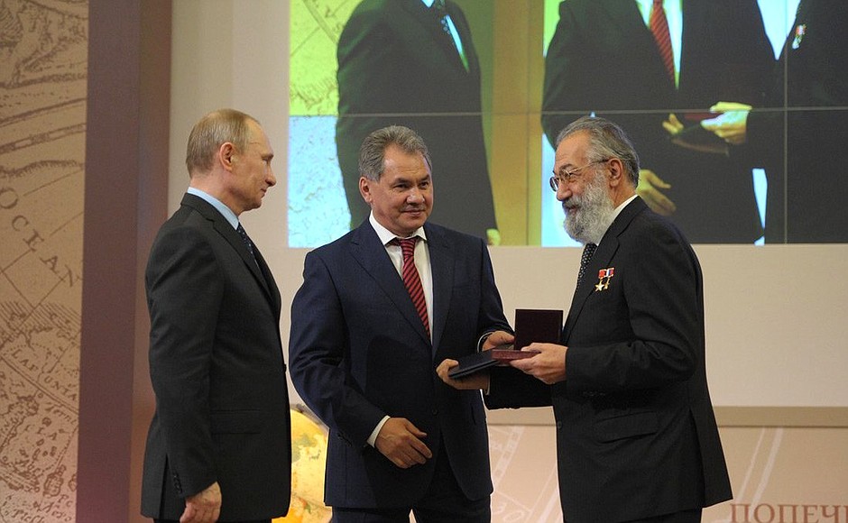 Vladimir Putin and Sergei Shoigu present the Grand Gold Medal to Professor, Doctor of Geography, corresponding member of the Russian Academy of Sciences, First Vice President of the Russian Geographical Society Artur Chilingarov.