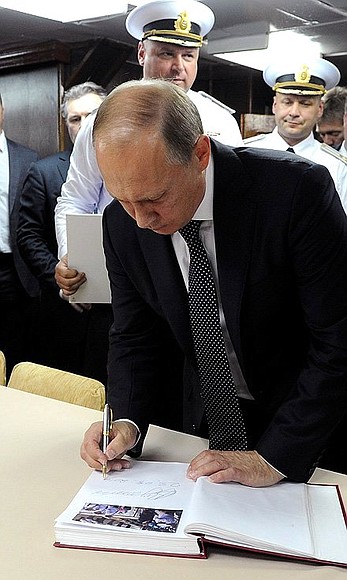 Vladimir Putin signs the distinguished visitors’ book on board the large anti-submarine ship Vice Admiral Kulakov.