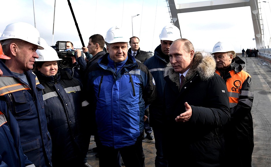 During the inspection of the completed road section of the Crimean Bridge. Speaking with construction workers.