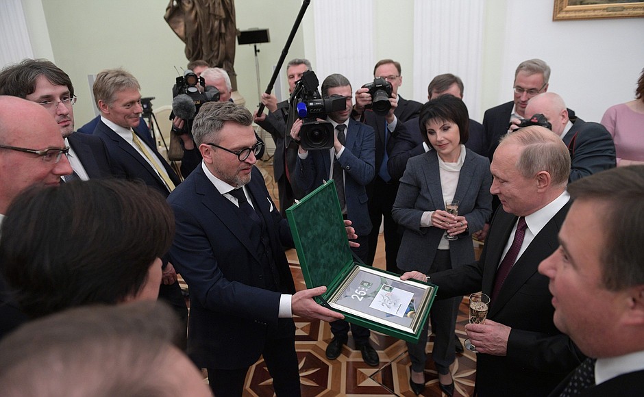 NTV staff presents Vladimir Putin with a commemorative postage stamp issued for the 25th anniversary of the television company.