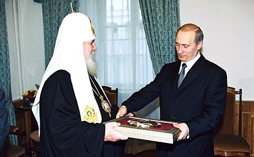 Patriarch of Moscow and All Russia Alexy II handing President Putin the badge and diploma of a winner of the prize for “Distinguished Activity in Reinforcing the Unity of Orthodox Peoples”.