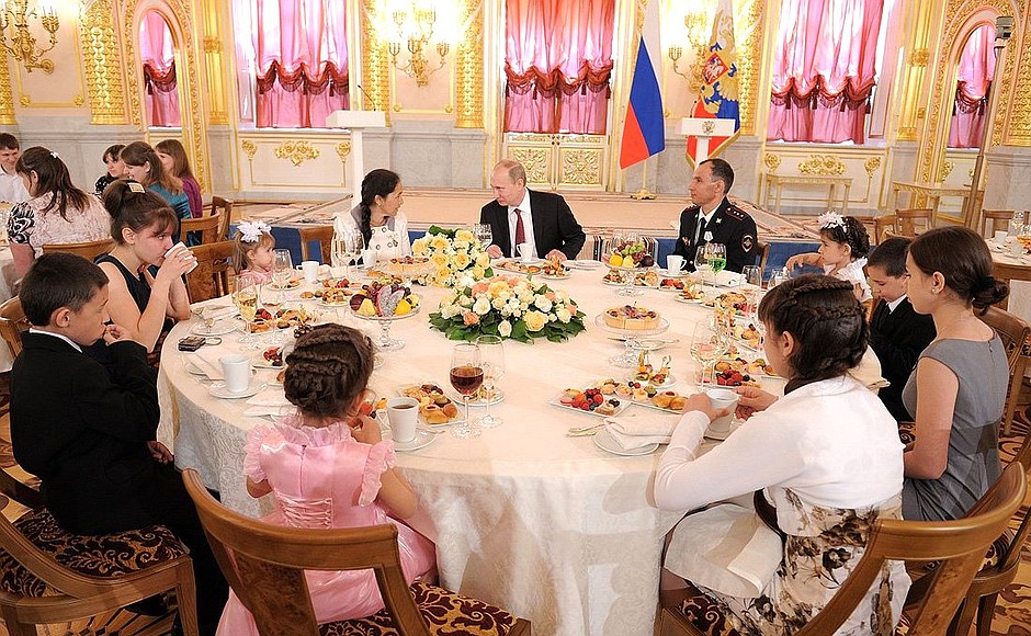 Vladimir Putin at the table with the family of Gulnara and Anatoly Bely, who are raising 8 children.