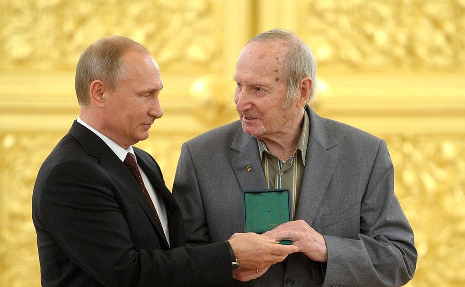 Vladimir Putin returns the 1956 Olympic gold medal to Viktor Shuvalov, a player on the USSR national ice hockey team.