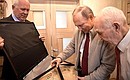 Vladimir Putin gives Lazar Matveyev a presidential watch and a copy of Pravda newspaper published on Mr Matveyev’s date of birth in 1927. With Rostec CEO Sergei Chemezov (left) .