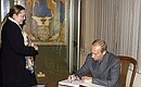 President Putin signing the visitors\' book of the State Tretyakov Gallery. Yekaterina Seleznyova, the chief curator of the gallery, left.