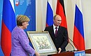 Vladimir Putin gives Angela Merkel a lithography dated late 19th century and depicting the signing of a Russian-German trade agreement.