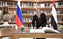 Vladimir Putin signs the distinguished visitors’ book at the presidential library of the Qasr Al Watan Palace.